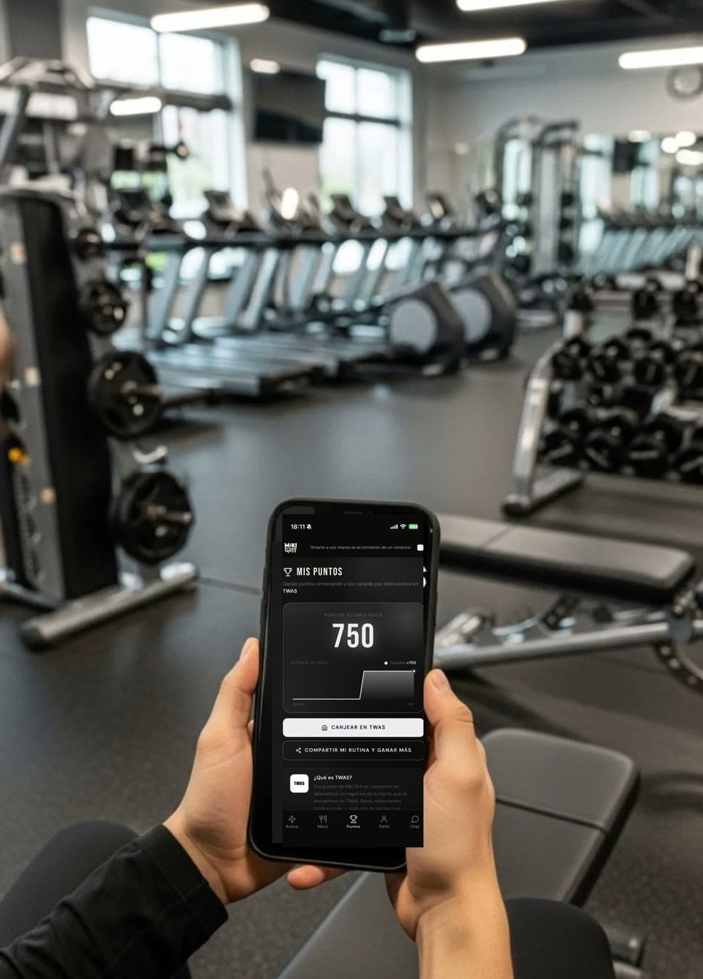 Mano sosteniendo un celular con la pantalla Mis Puntos de Miki Grit, en un gimnasio
